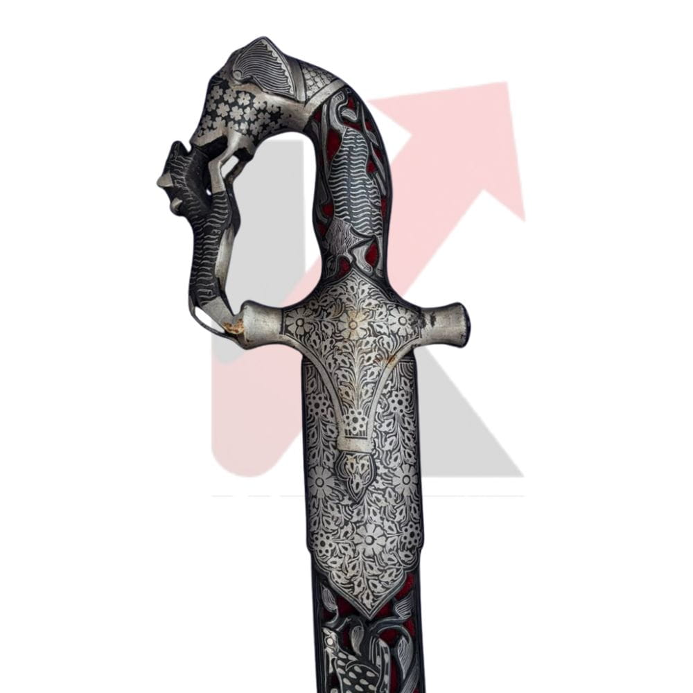 An ornate miniature sword with intricate silver filigree patterns, dark gray pommel, and red accents, shown against a white background with a faint kraftmart watermark 