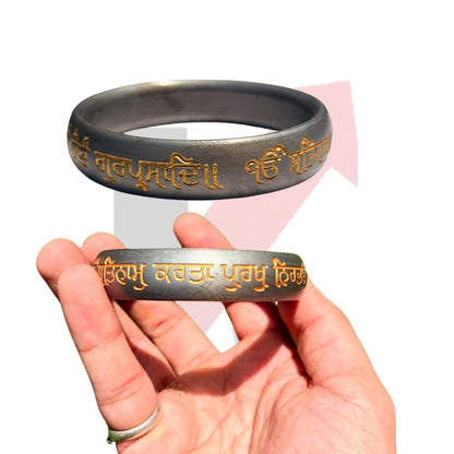 A hand holding a metallic silver-toned bracelet with gold-colored Tibetan script, with a larger, clearer view of the same bracelet floating above the hand against a white background with a faint kraftmart  graphic.